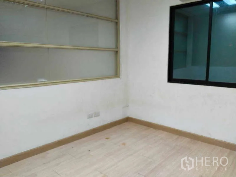 Office Space for rent in Bang Na, Bangkok - Corner office with internal glass window, power outlets, and neutral walls.