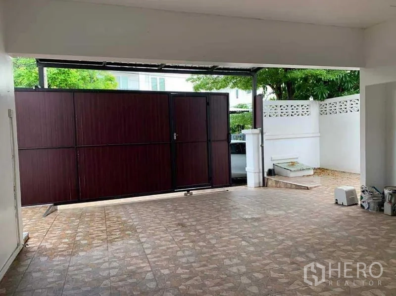 Detached House for sale in Sai Mai, Bangkok - Close view of the covered carport and dark wood sliding entrance gate.