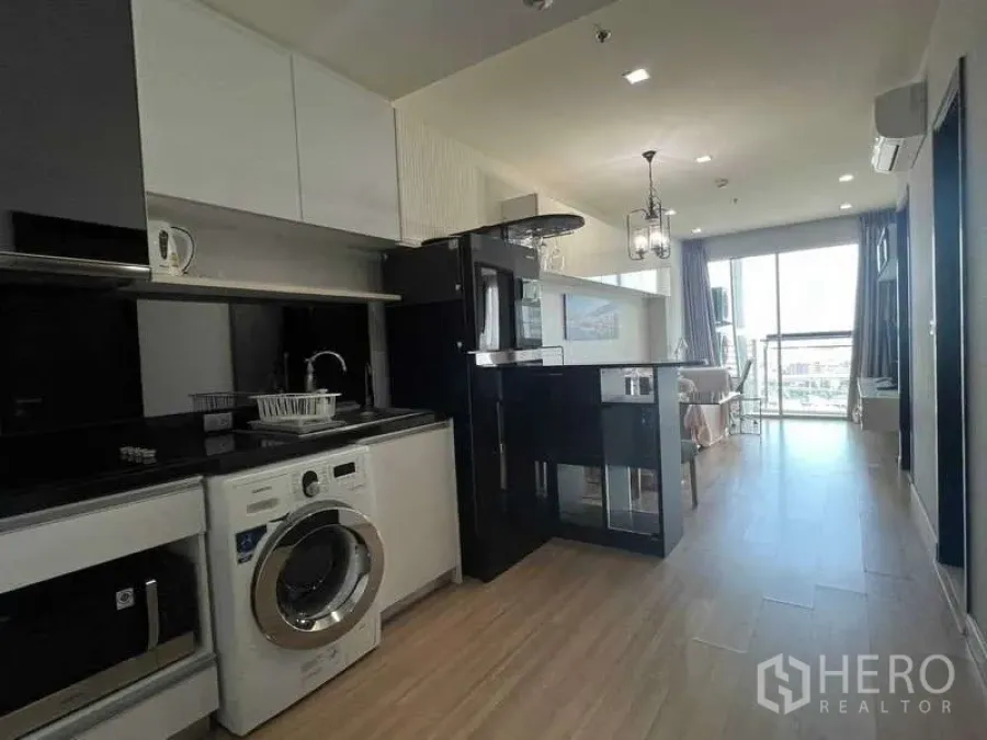 Condominium for sale in Khlong Toei, Bangkok - Another view of the open kitchen and breakfast bar looking toward the balcony and skyline.