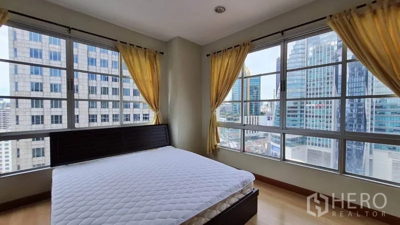 Condominium for rent in Khlong Toei, Bangkok - Corner bedroom with wraparound windows, panoramic skyline view, and a queen bed.