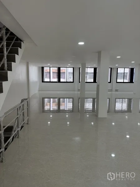 Office Space for rent or sale in Huai Khwang, Bangkok - Open office area beside a wrapped metal stair railing and black-framed windows.