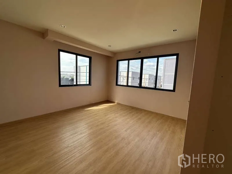 Factory for rent or sale in Lam Luk Ka, Pathum Thani - Corner office with large windows and wood-style flooring allowing natural light.