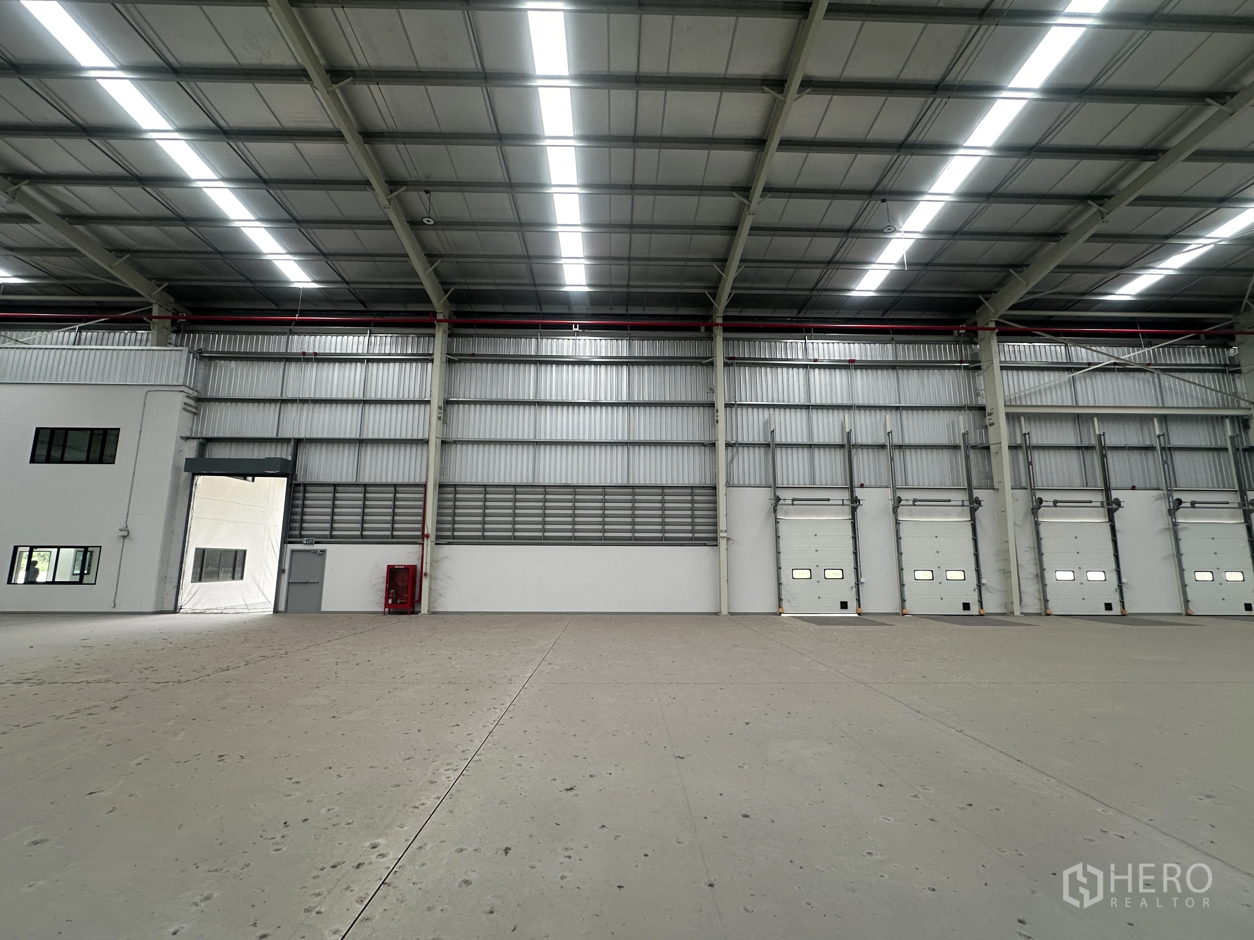 Warehouse for rent in Mueang Chon Buri, Chon Buri - View of dock doors, a fire hose cabinet, and an entry to the side office.