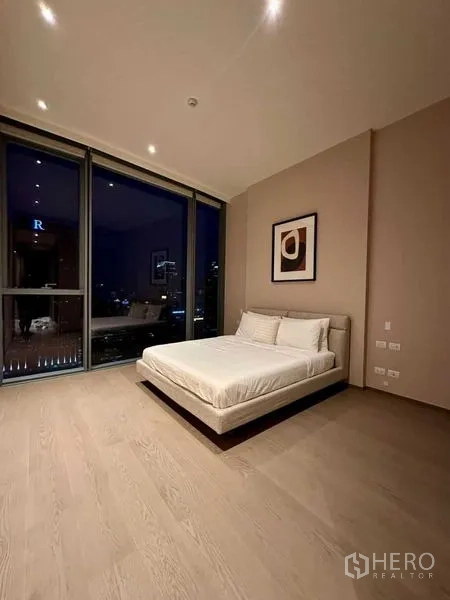 Condominium for rent or sale - Spacious bedroom at night with glass wall and balcony outlook.