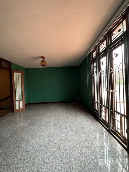 联排别墅 出租在Khlong Toei, Bangkok - 客厅采光充足，落地门、绿色背景墙与花岗岩地面。