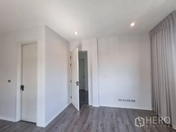 Detached House for rent - Minimalist bedroom corner with recessed lights, grey wood flooring and two white doors.