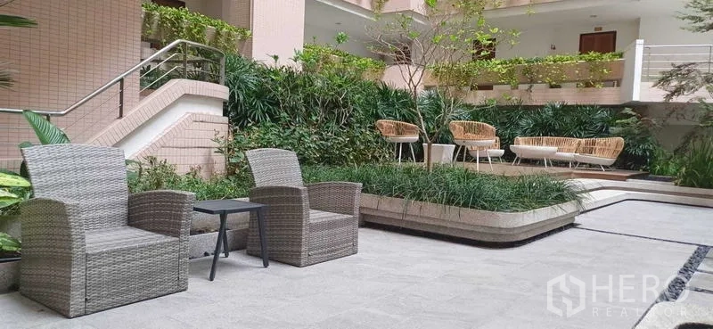 Condominium for sale in Pathum Wan, Bangkok - Shaded outdoor lounge with wicker seating and lush planters in the condominium courtyard.