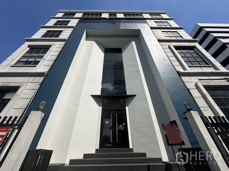 Retail Space for rent in Phra Khanong, Bangkok - Modern commercial building facade in Phra Khanong with a tall glass entrance and geometric design under a blue sky.