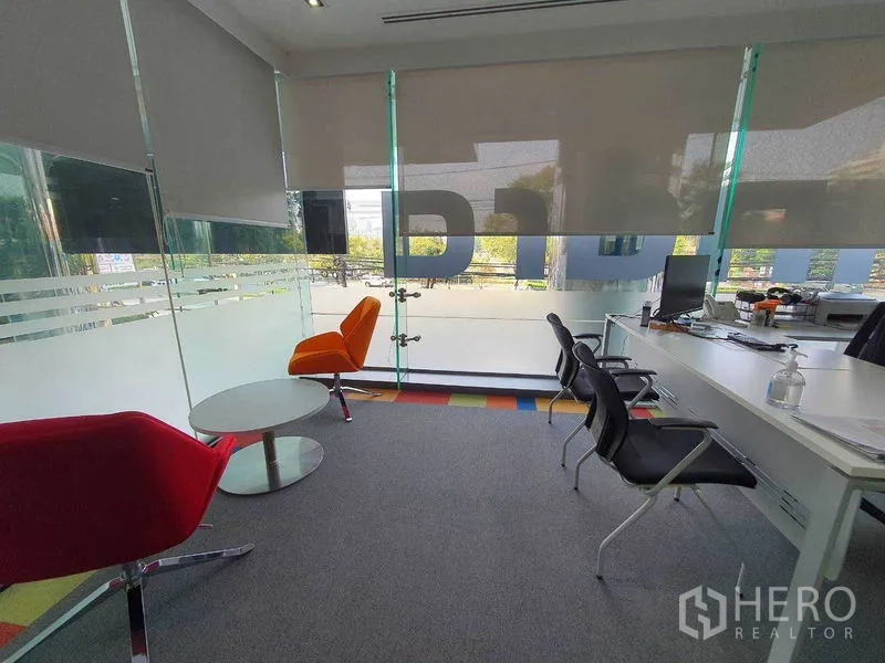 Office Space for rent in Ratchathewi, Bangkok - Small meeting area with round table, colorful lounge chairs, and floor-to-ceiling windows.