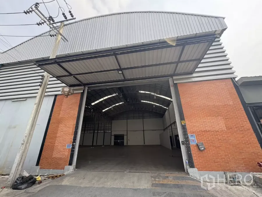 Warehouse for rent in Bang Phli, Samut Prakan - Front view of a high-bay warehouse with a large entrance and brick-and-metal exterior.