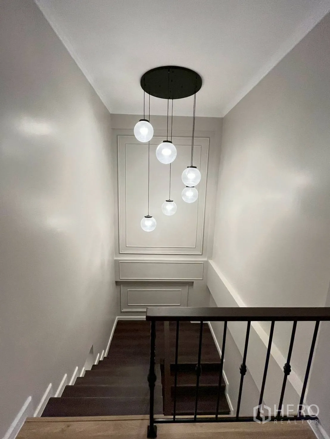 Townhouse for rent in Khlong Toei, Bangkok - Stairwell with hanging globe pendant lights and paneled wall detail.
