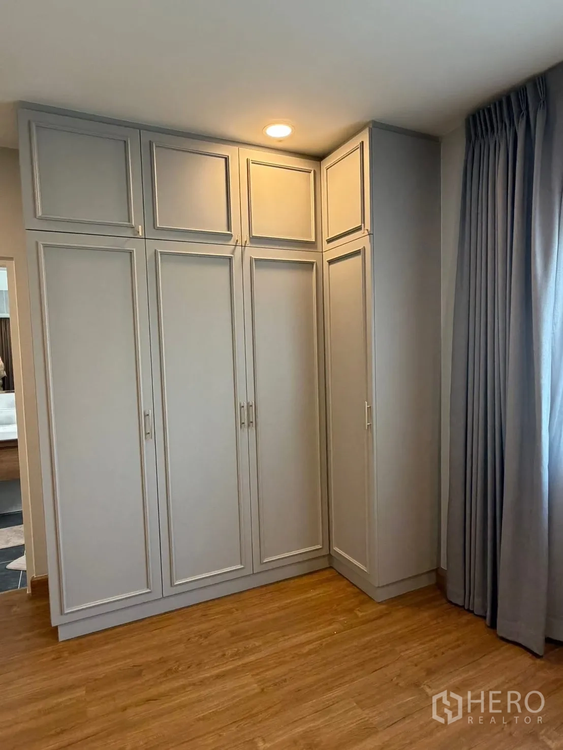 Detached House for rent in Bang Phli, Samut Prakan - Built-in corner wardrobe with gray paneled doors beside full-length curtains.