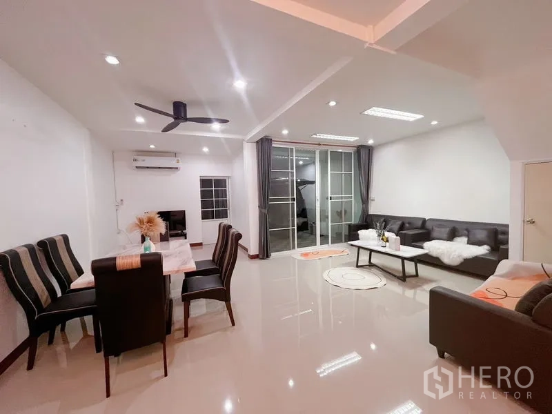 Townhouse for rent in Huai Khwang, Bangkok - Wide view of open-plan lounge and dining with glossy floors and downlights.