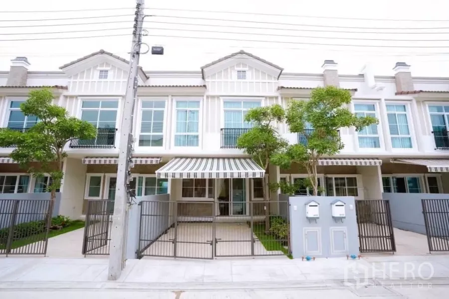 Townhouse for rent in Bang Phli, Samut Prakan - European-style townhouse facade with striped awning, gated carport and front trees
