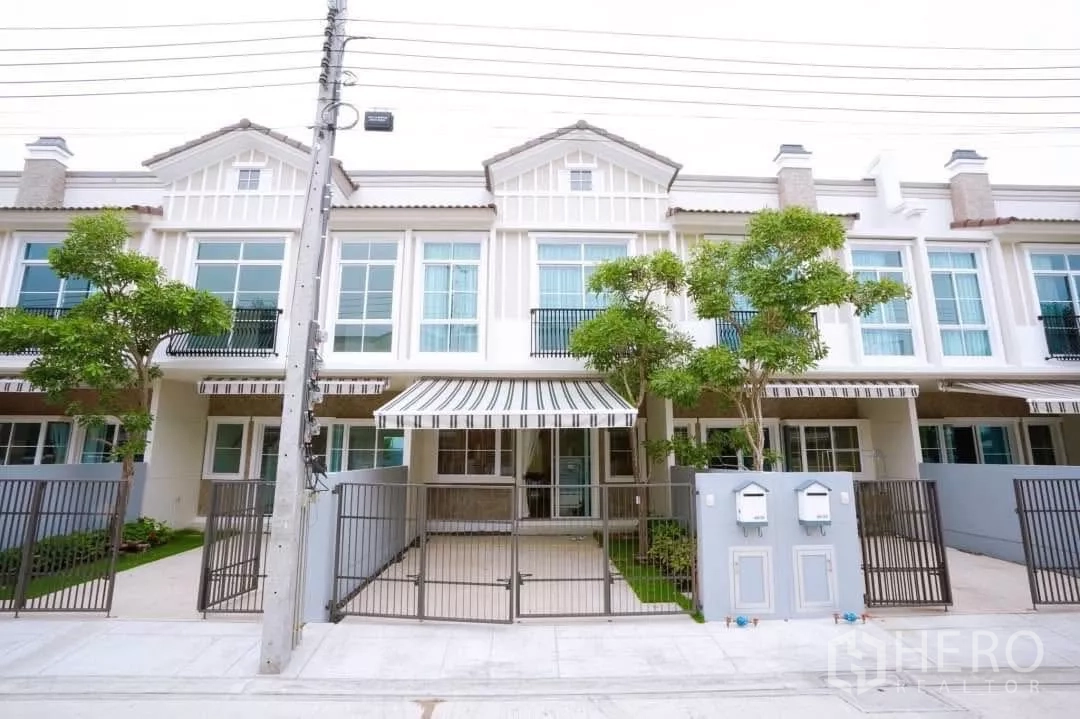 Townhouse for rent in Bang Phli, Samut Prakan - European-style townhouse facade with striped awning, gated carport and front trees