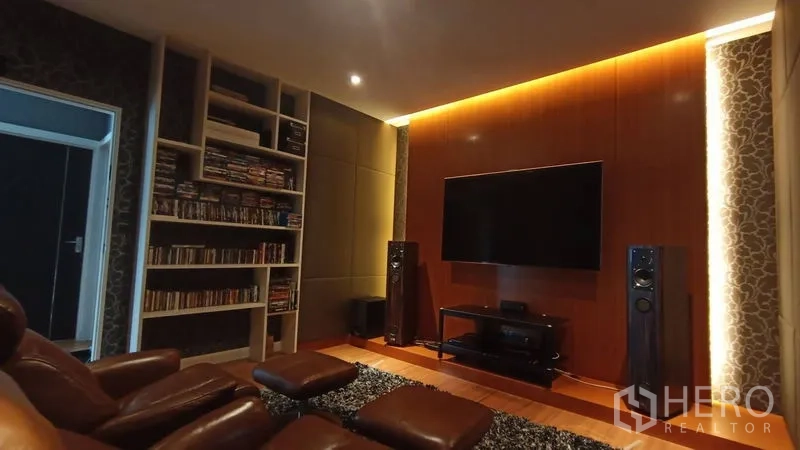Detached House for sale in Prawet, Bangkok - Cozy home theater with leather recliners, built-in bookcase, large TV and ambient lighting.