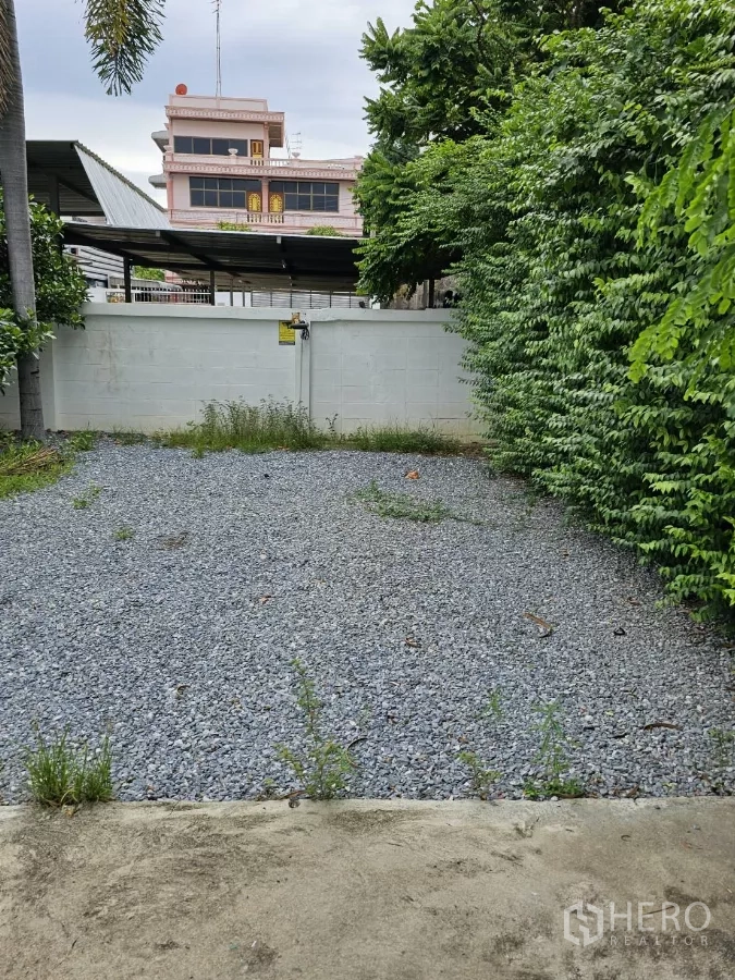 Detached House for rent or sale in Lat Phrao, Bangkok - Gravel parking bay by the rear gate surrounded by greenery.