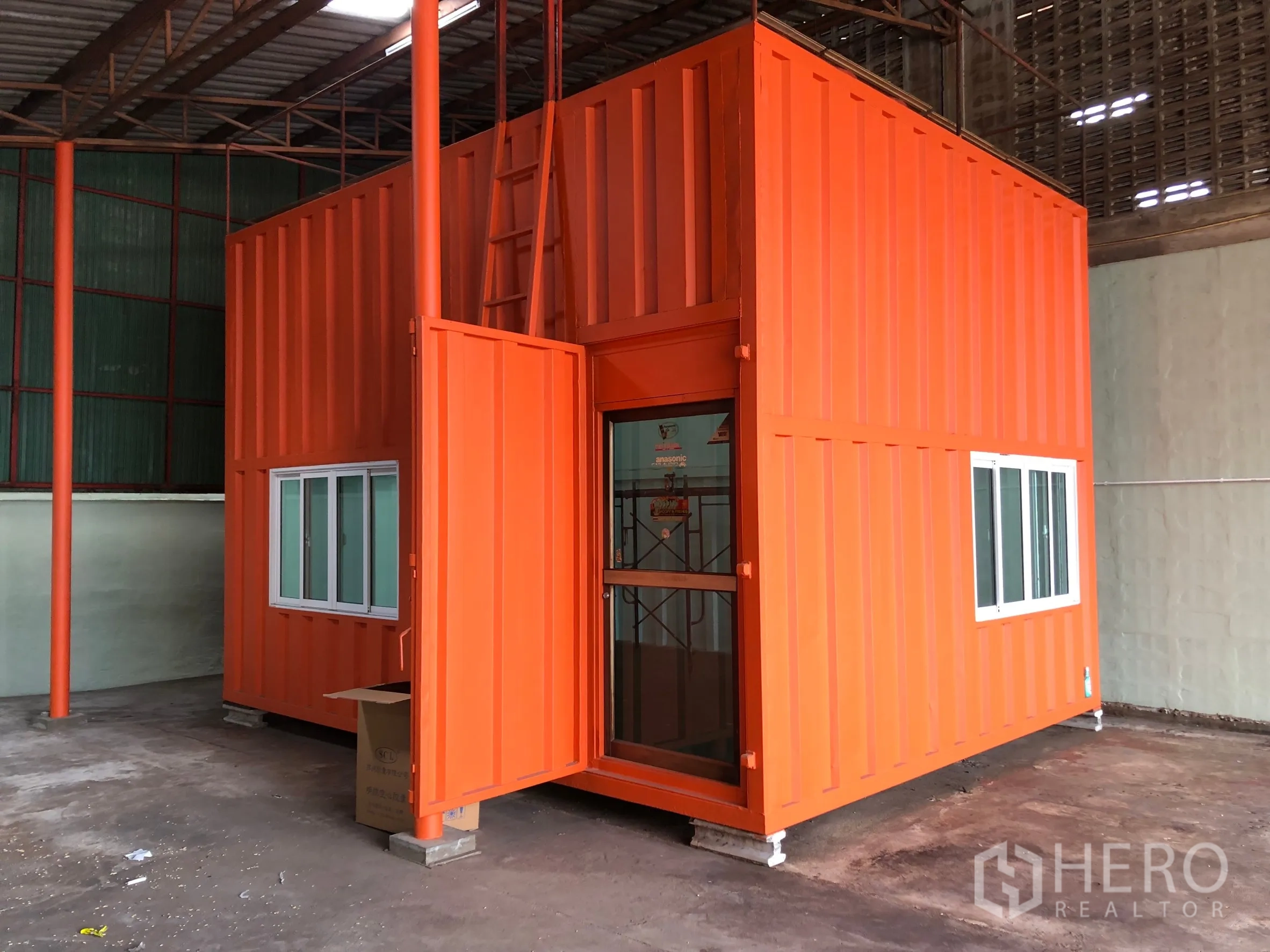 Warehouse for rent in Min Buri, Bangkok - Bright orange container-style office inside the warehouse with windows and a glass entry door.