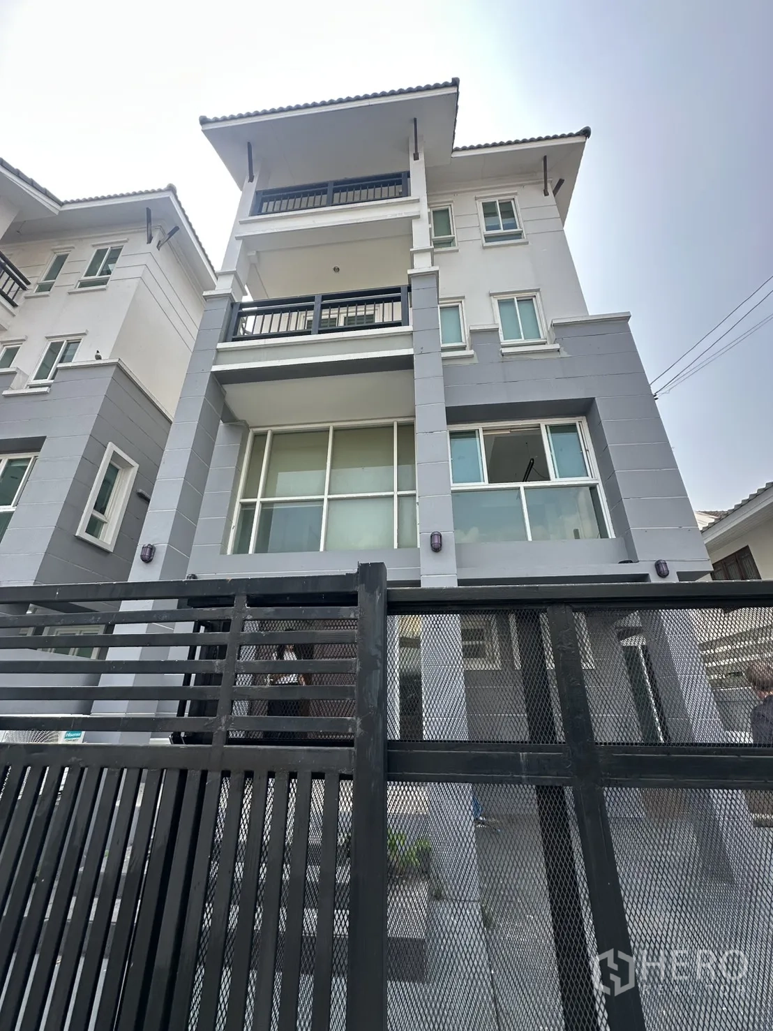 Home Office for rent in Watthana, Bangkok - Four-storey home office facade with balconies, large glass windows and a black metal gate.