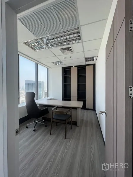 办公空间 出租在Huai Khwang, Bangkok - 独立办公室，配行政桌与内置书柜，大窗可见曼谷天际线。