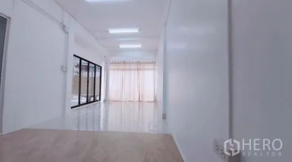 Townhouse for sale - Long corridor-style living area with ceiling lights and sheer curtains.