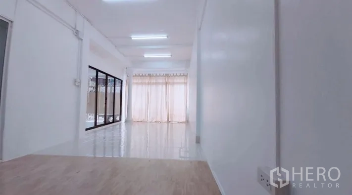 Townhouse for sale - Long corridor-style living area with ceiling lights and sheer curtains.