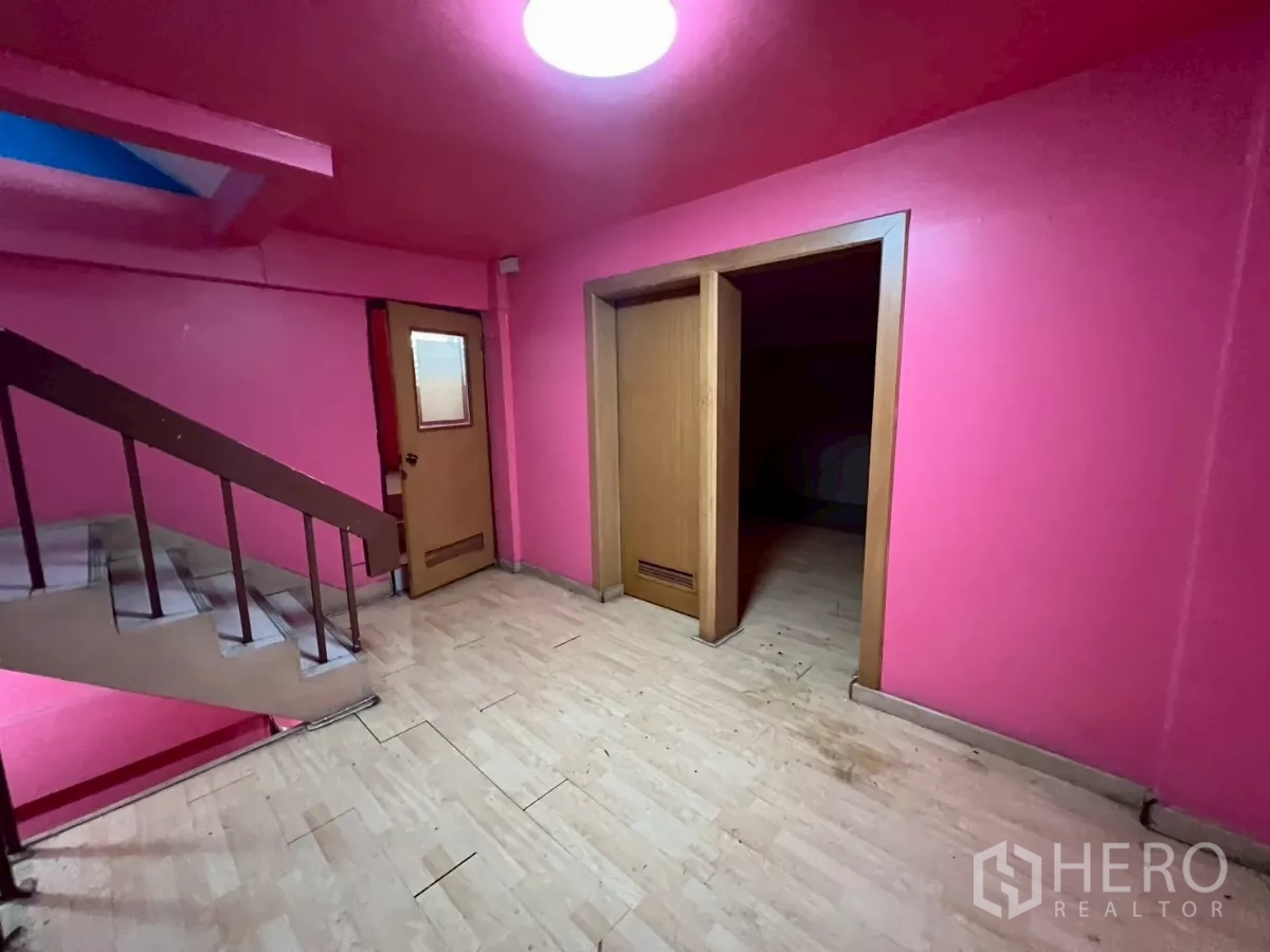 Shophouse for rent in Watthana, Bangkok - Stair landing with pink walls, wood doors, and an internal staircase.