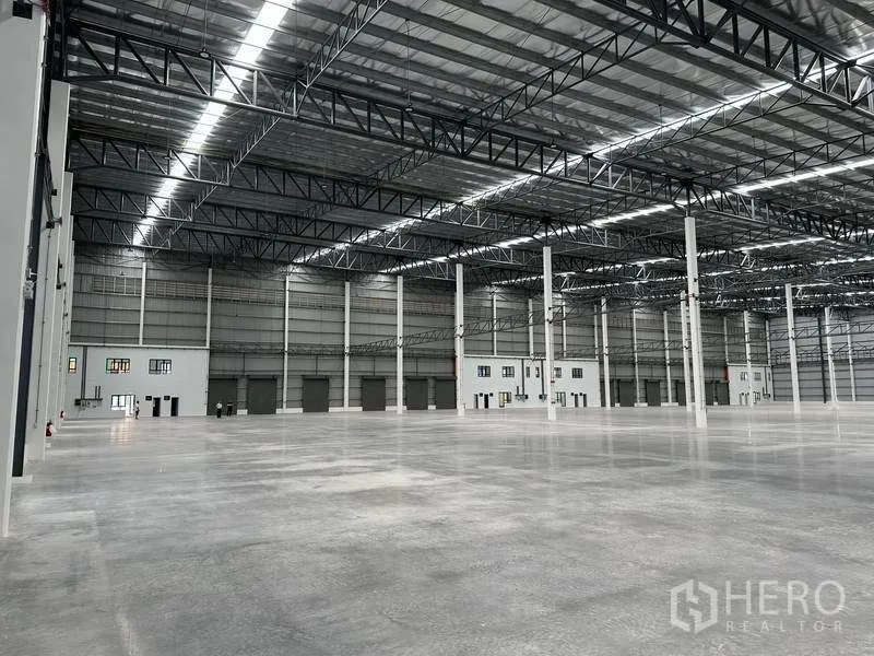 Factory for rent in Bang Phli, Samut Prakan - Expansive factory floor facing multiple loading doors beneath a skylit metal roof.