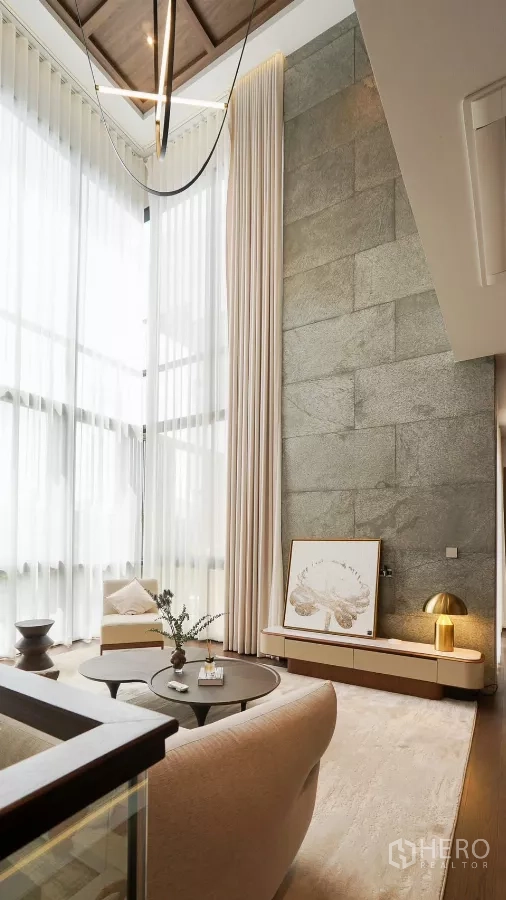 Detached House for rent or sale in Bang Kapi, Bangkok - Mezzanine lounge with textured stone wall, modern pendant and glass balustrade.