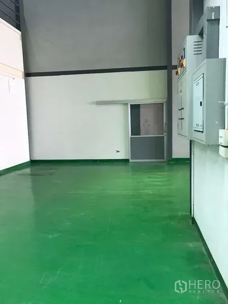 Factory for rent in Bang Phli, Samut Prakan - Clean corridor with green epoxy floor leading to a sliding door and power panels.