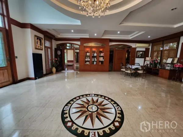 Detached House for rent in Prawet, Bangkok - Grand foyer with marble floor and compass medallion, built‑in wooden cabinetry and chandelier lighting.