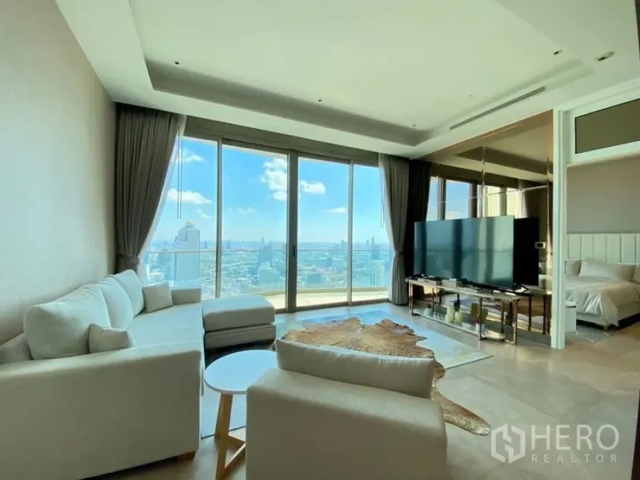 Condominium for rent in Khlong San, Bangkok - Bright living room with TV unit, wide glazing to the balcony, and a glimpse of the adjacent bedroom.