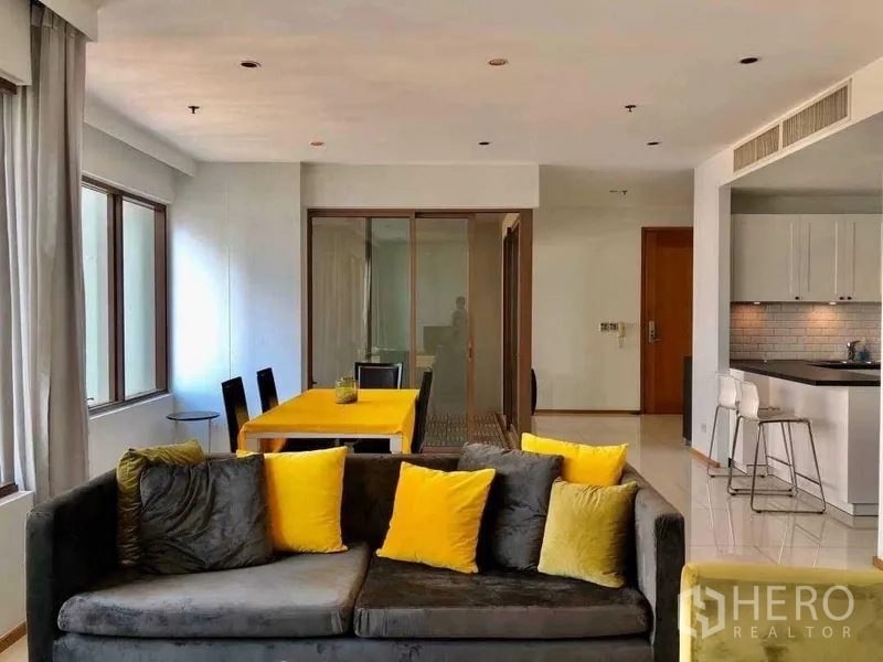 Condominium for sale in Khlong Toei, Bangkok - Living room facing dining table and kitchen with recessed lights and sliding glass room.