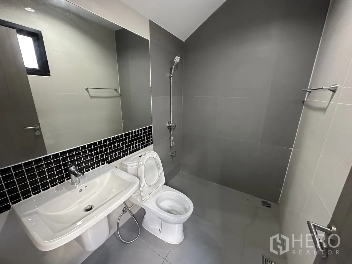 Home Office for rent or sale in Suan Luang, Bangkok - Contemporary bathroom with walk-in shower, long mirror, sink and toilet finished in grey tiles.