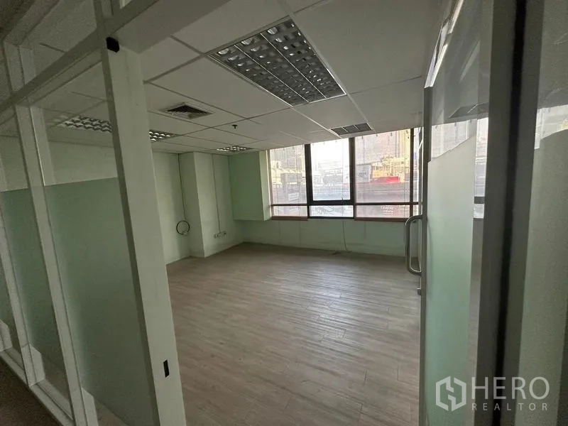 办公空间 出租 - 转角办公室，玻璃门进入，吊顶灯具与整面窗户带来通透感。