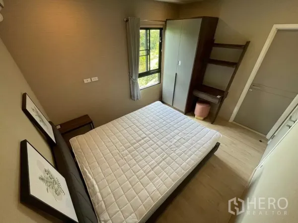 Townhouse for rent in Suan Luang, Bangkok - Cozy bedroom with queen bed, wardrobe, corner desk and sunlight from a side window.