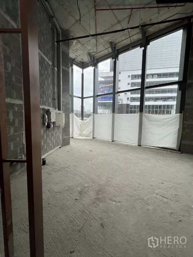 Retail Space for rent - Bare‑shell retail space with exposed ceiling services, concrete floor and tall corner windows facing the city.