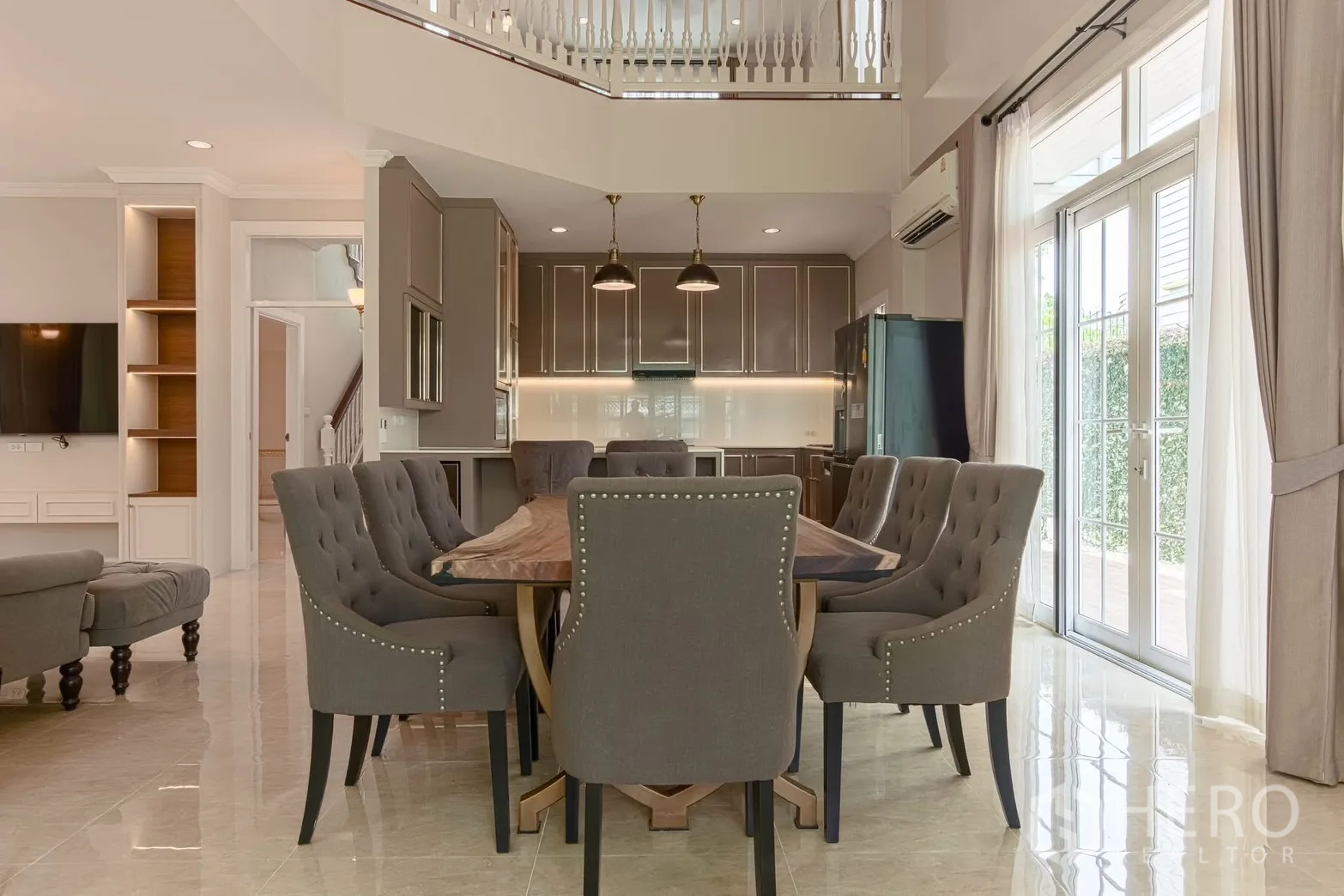 Detached House for rent in Bang Na, Bangkok - Double-height dining room with large table, gray chairs, and kitchen backdrop.