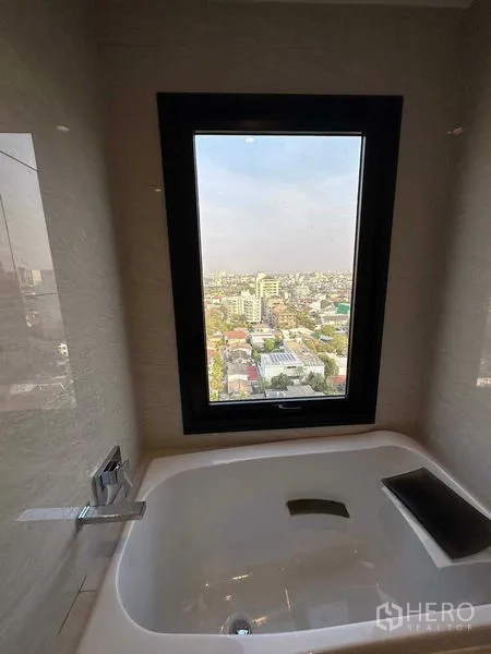 Condominium for sale - Bathtub beside a picture window with sweeping Bangkok cityscape views.