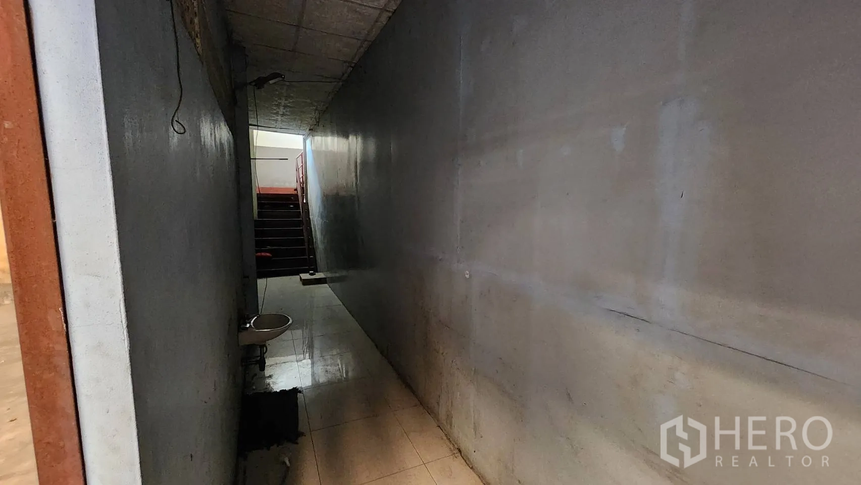 Warehouse for rent in Nonthaburi - Narrow internal corridor with a sink leading toward a staircase.
