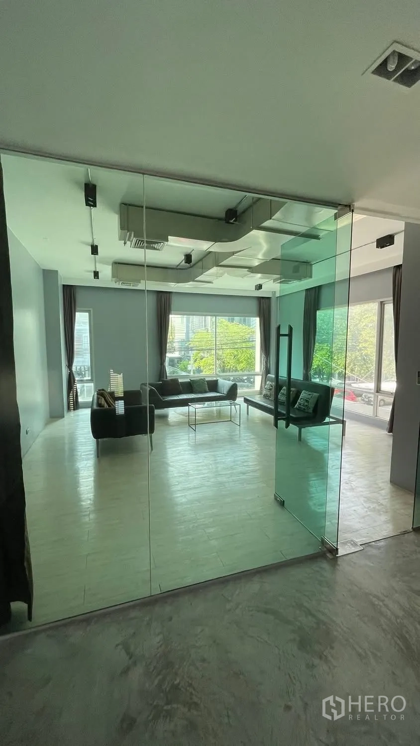 Home Office for rent or sale in Wang Thonglang, Bangkok - Spacious room seen through floor-to-ceiling glass partitions with large windows.