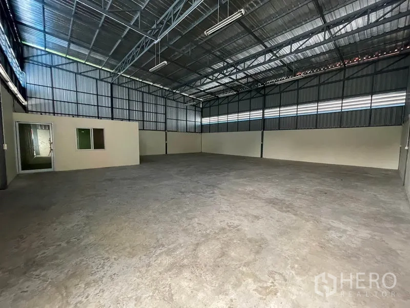 Warehouse for rent in Khlong Luang, Pathum Thani - Open-plan storage area with strip windows, lighting and metal wall panels.