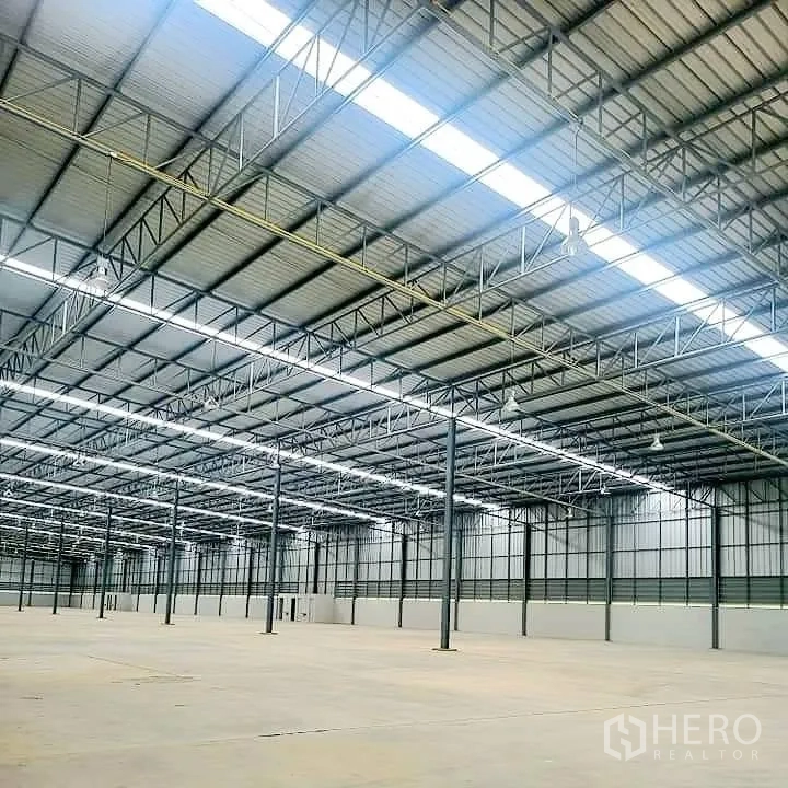 Warehouse for rent in Lat Krabang, Bangkok - Close view of the warehouse roof structure with steel trusses, skylight panels, and lighting fixtures.