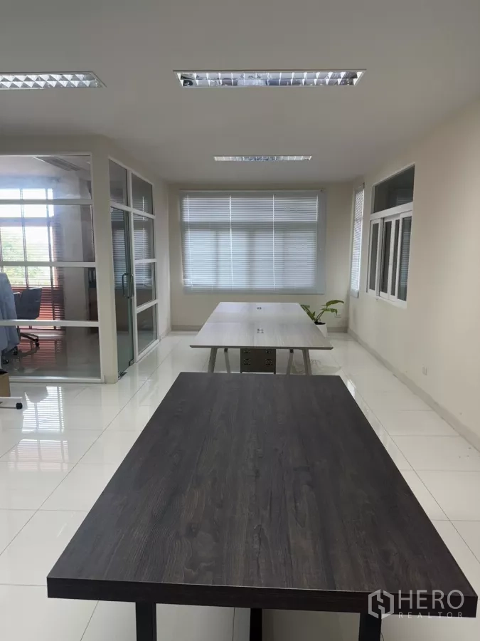Factory for sale in Lam Luk Ka, Pathum Thani - Open-plan office with long worktables, glass-partition room and window blinds.