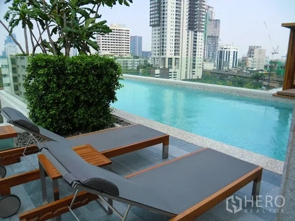 Condominium for rent or sale in Watthana, Bangkok - Rooftop infinity pool with sun loungers and Bangkok skyline views.
