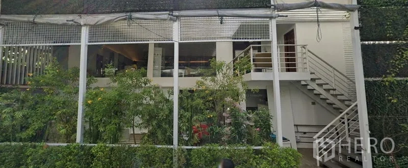 Retail Space for rent in Khlong Toei, Bangkok - Two-level retail space with mezzanine, exterior staircase, and lush green facade.