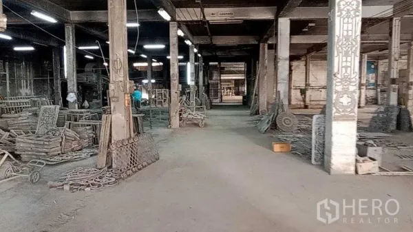 Warehouse for rent in Nakhon Pathom - Spacious factory floor with concrete columns, overhead lighting and storage racks inside the warehouse.