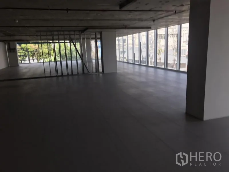 Office Space for rent in Khlong Toei, Bangkok - Open-plan office floor in Phra Khanong with floor-to-ceiling windows, city views, tiled flooring and an exposed ceiling.