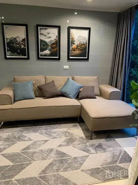 Townhouse for rent in Suan Luang, Bangkok - Cozy second lounge with beige chaise sofa, patterned rug and framed wall art near a large window.