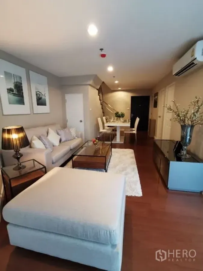 Condominium for rent or sale in Huai Khwang, Bangkok - Alternate angle of the living room showing sofa, ottoman and connected dining area.